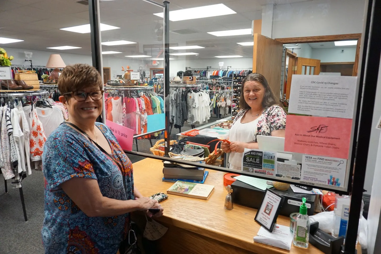 A volunteer and a shopper sharing a smile at the checkout counter